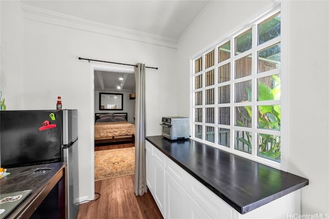 kitchen with stainless steel refrigerator, white cabinetry, crown molding, and dark hardwood / wood-style floors