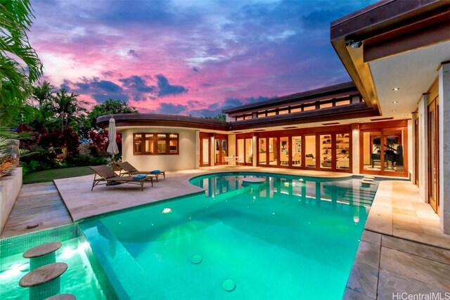 pool at dusk featuring a patio