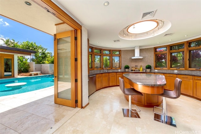 kitchen with dishwasher, sink, decorative backsplash, and wall chimney range hood