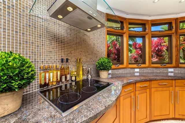 kitchen featuring island exhaust hood, electric stovetop, backsplash, and dark stone counters