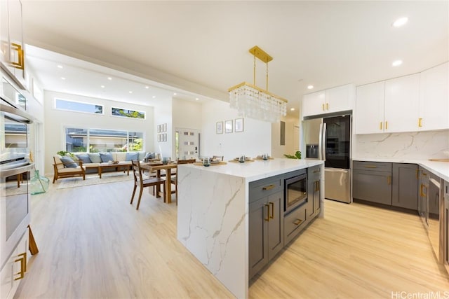 kitchen with white cabinets, decorative light fixtures, tasteful backsplash, stainless steel fridge, and built in microwave