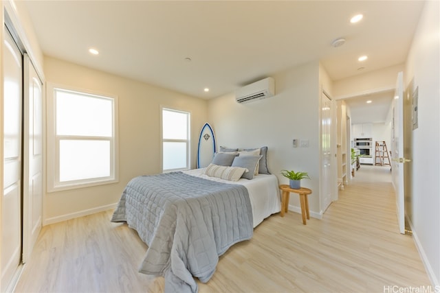 bedroom with light wood-type flooring and a wall unit AC