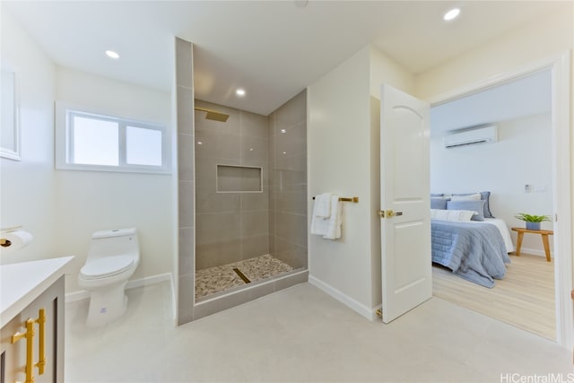 bathroom with tiled shower, toilet, a wall unit AC, and vanity