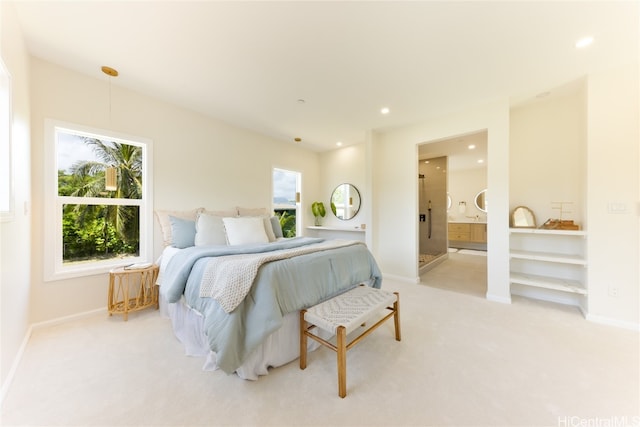 bedroom featuring multiple windows, connected bathroom, and light carpet