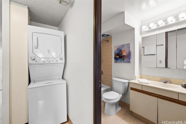 full bathroom with a textured ceiling, toilet, vanity, stacked washing maching and dryer, and tiled shower / bath combo