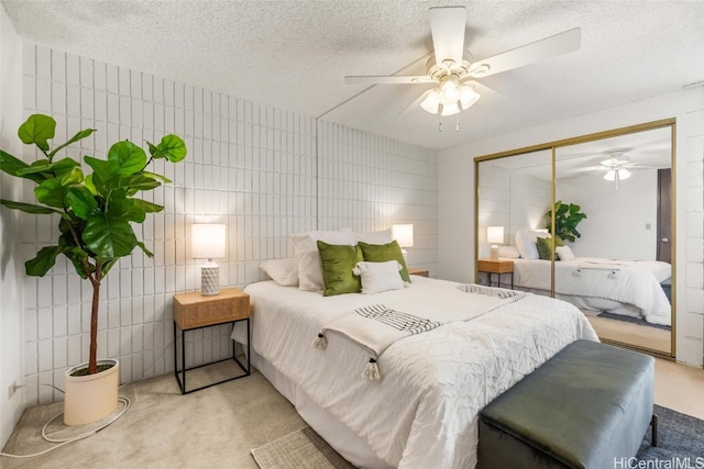 bedroom featuring light carpet, ceiling fan, a textured ceiling, tile walls, and a closet