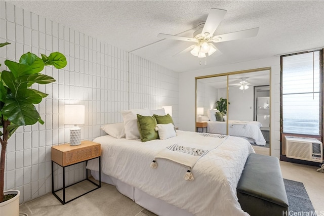 bedroom featuring light carpet, ceiling fan, a textured ceiling, tile walls, and a closet