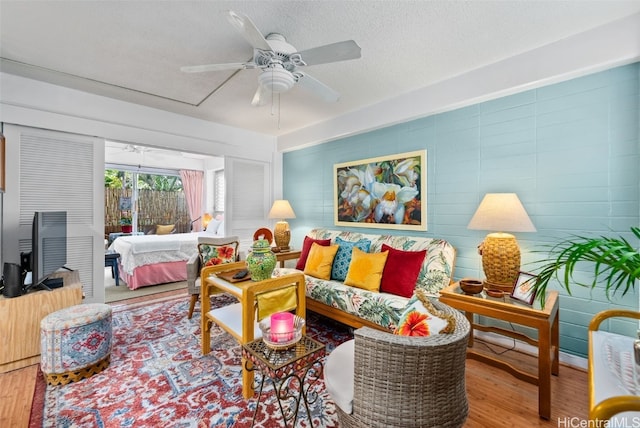 living room featuring ceiling fan, hardwood / wood-style flooring, and a textured ceiling