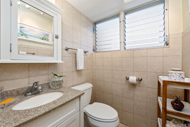 bathroom featuring vanity, toilet, tile walls, and a wealth of natural light