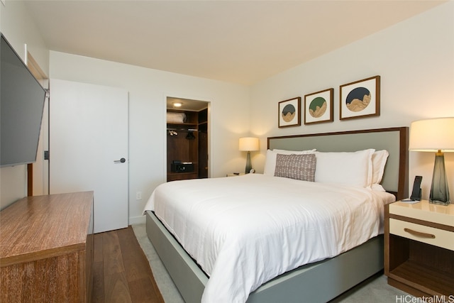 bedroom featuring dark wood-type flooring, a walk in closet, and a closet