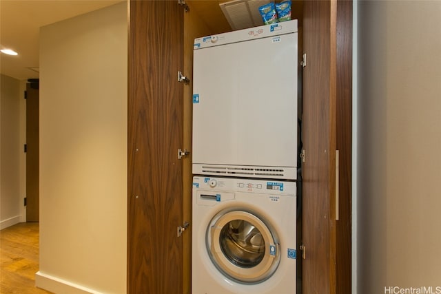 clothes washing area with stacked washer / dryer and light wood-type flooring