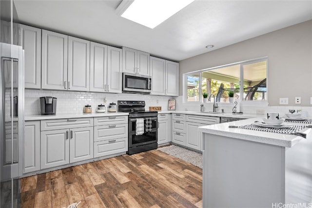 kitchen featuring kitchen peninsula, stainless steel appliances, dark hardwood / wood-style floors, and sink