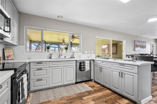 kitchen featuring kitchen peninsula, a wealth of natural light, sink, and dark wood-type flooring