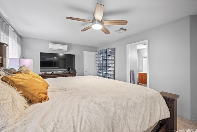 carpeted bedroom with ensuite bath, a wall mounted AC, and ceiling fan