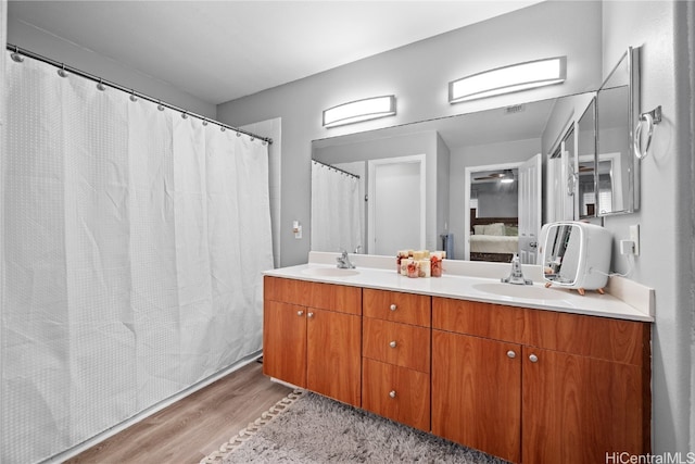 bathroom with a sink, double vanity, connected bathroom, and wood finished floors