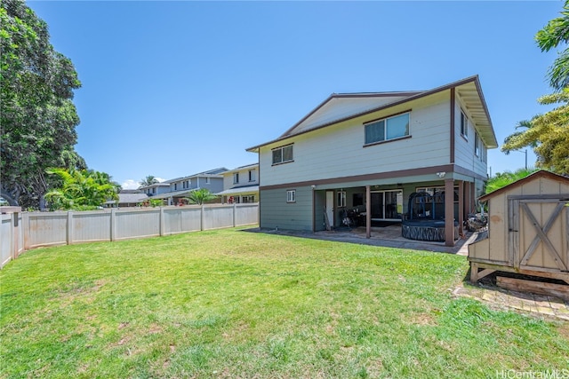 back of property featuring a shed, a lawn, a patio area, and a fenced backyard