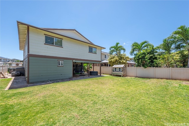 back of house with an outbuilding, a yard, a shed, and a fenced backyard