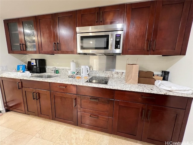 kitchen featuring sink, black electric stovetop, and light stone counters