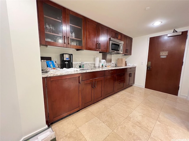 223 Saratoga Rd Unit 1108, Honolulu, HI 96815 - kitchen with stainless steel microwave, glass insert cabinets, light tile patterned flooring, light stone countertops, and a sink