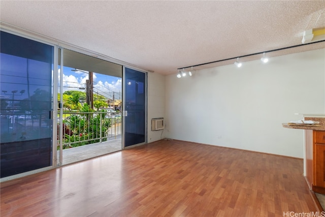 empty room featuring expansive windows, a textured ceiling, and hardwood / wood-style floors