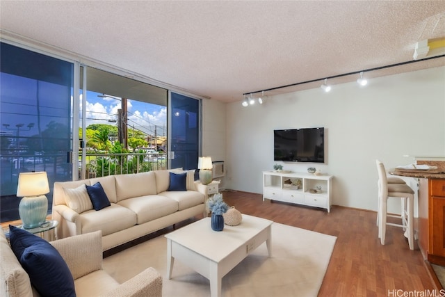 living room featuring hardwood / wood-style floors, a wall of windows, and a textured ceiling