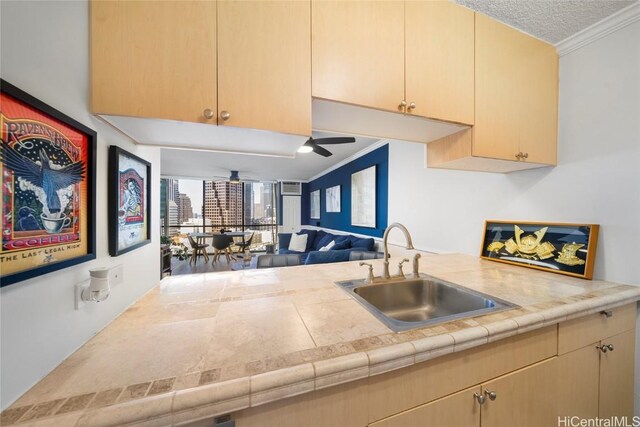 kitchen with kitchen peninsula, light brown cabinetry, crown molding, ceiling fan, and sink