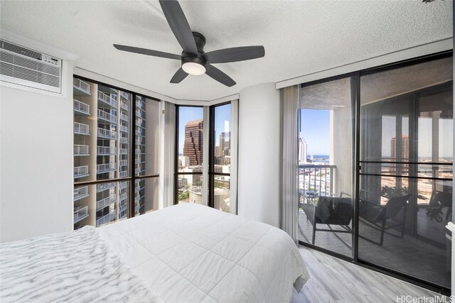 bedroom with a wall of windows, multiple windows, access to exterior, and ceiling fan