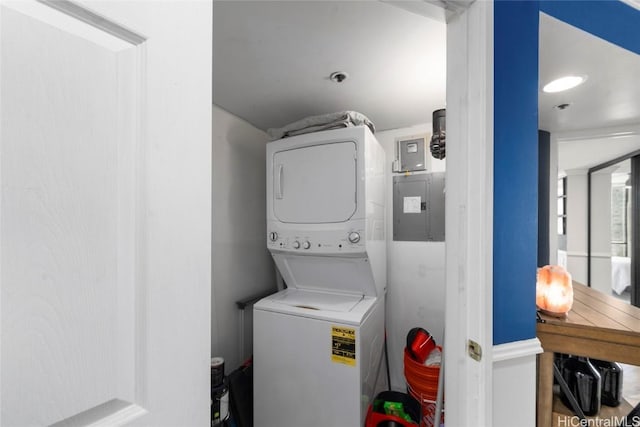 laundry room with electric panel and stacked washer and clothes dryer