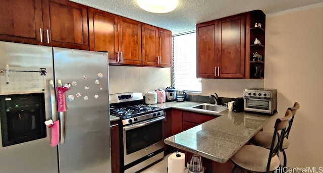 kitchen with sink, a kitchen bar, a textured ceiling, kitchen peninsula, and stainless steel appliances