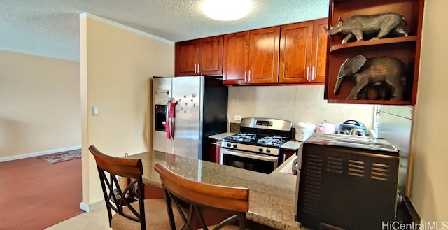 kitchen featuring appliances with stainless steel finishes, a textured ceiling, kitchen peninsula, light stone counters, and ornamental molding