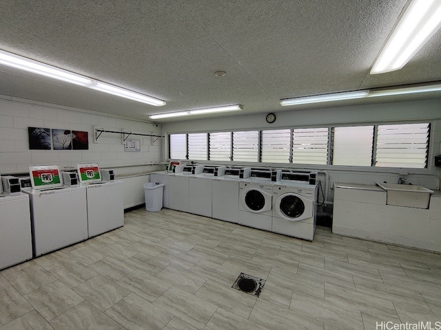 washroom with washer and dryer, a textured ceiling, and sink