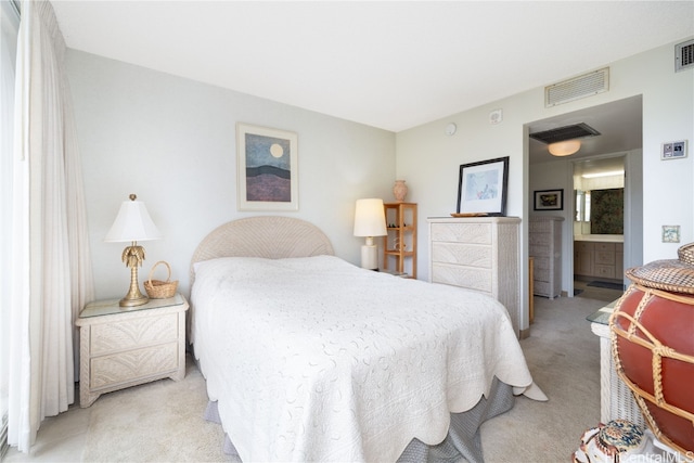 bedroom with ensuite bath and light colored carpet