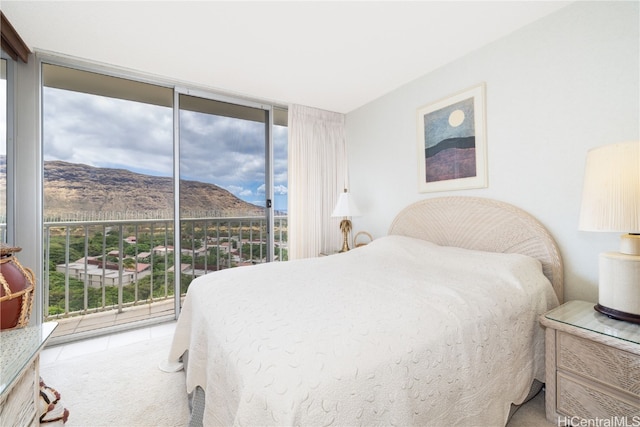 bedroom featuring expansive windows, a mountain view, multiple windows, and access to outside