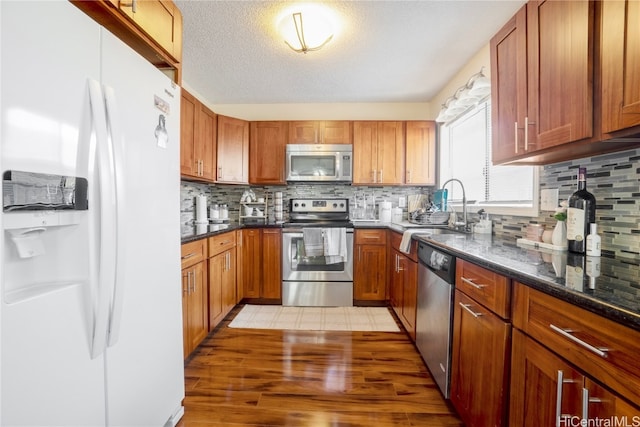 kitchen featuring light hardwood / wood-style floors, tasteful backsplash, appliances with stainless steel finishes, and a textured ceiling