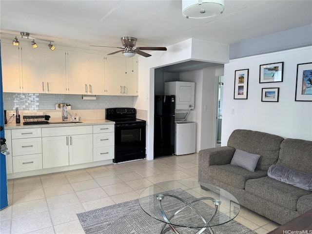 kitchen featuring ceiling fan, stacked washer and dryer, open floor plan, black appliances, and tasteful backsplash