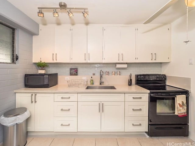 kitchen with sink, tasteful backsplash, black appliances, light tile patterned floors, and white cabinets