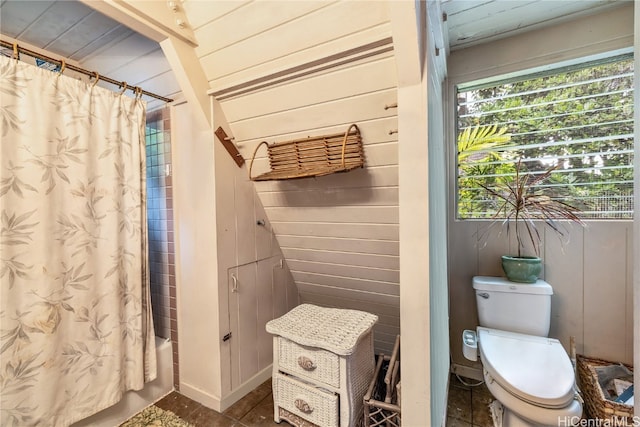 bathroom featuring toilet, wood walls, and shower / tub combo with curtain