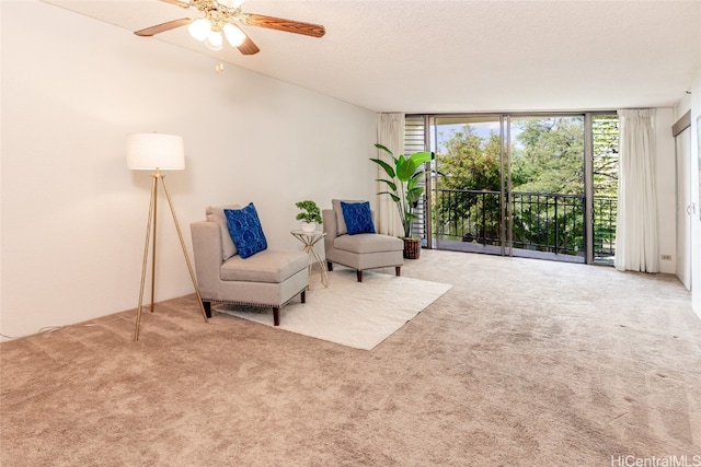 living area featuring floor to ceiling windows, a textured ceiling, carpet, and ceiling fan