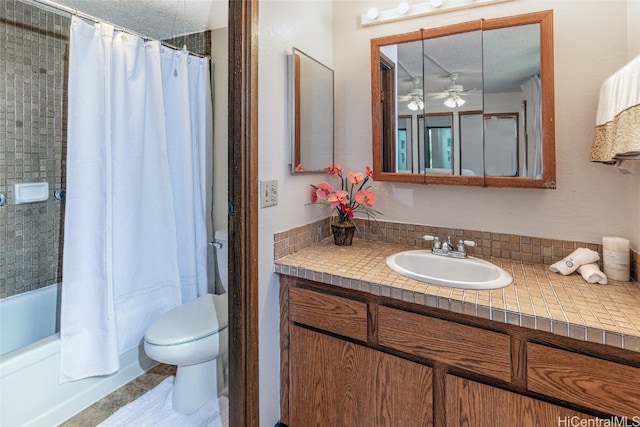 full bath featuring toilet, shower / bath combo with shower curtain, ceiling fan, a textured ceiling, and vanity