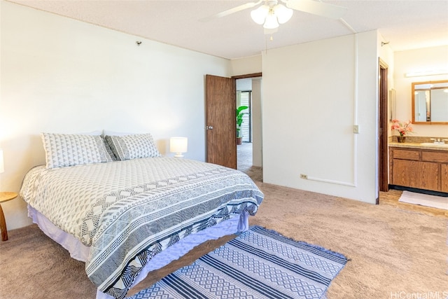 bedroom with ensuite bath, ceiling fan, a sink, and light colored carpet