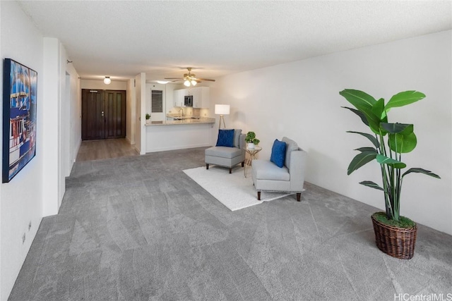 sitting room featuring a textured ceiling, carpet flooring, and a ceiling fan