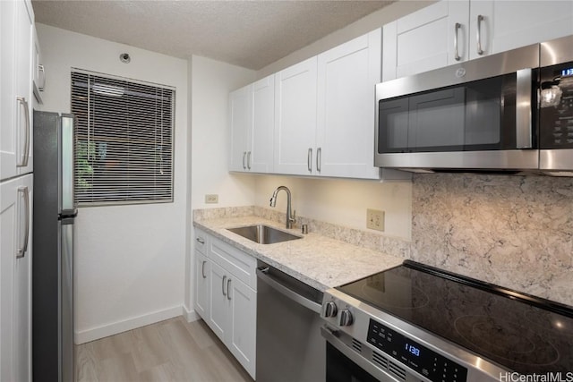 kitchen with white cabinetry, a textured ceiling, appliances with stainless steel finishes, and a sink