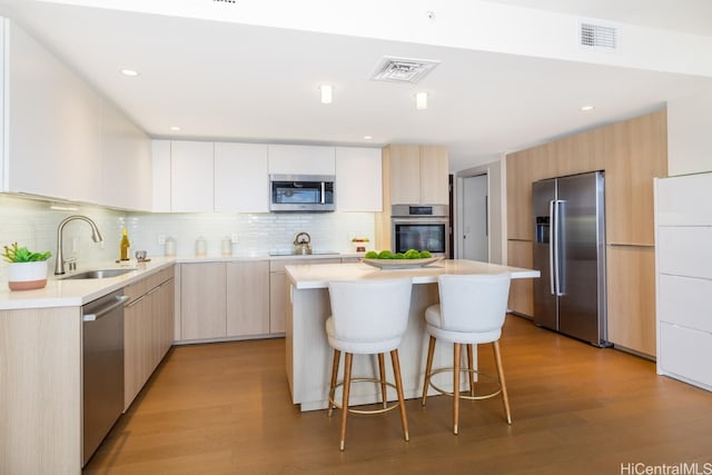 kitchen featuring sink, appliances with stainless steel finishes, a kitchen island, and light hardwood / wood-style floors