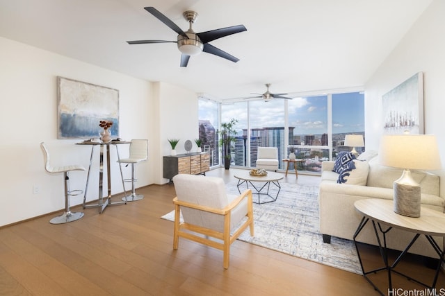 living room with ceiling fan, hardwood / wood-style flooring, and a wall of windows