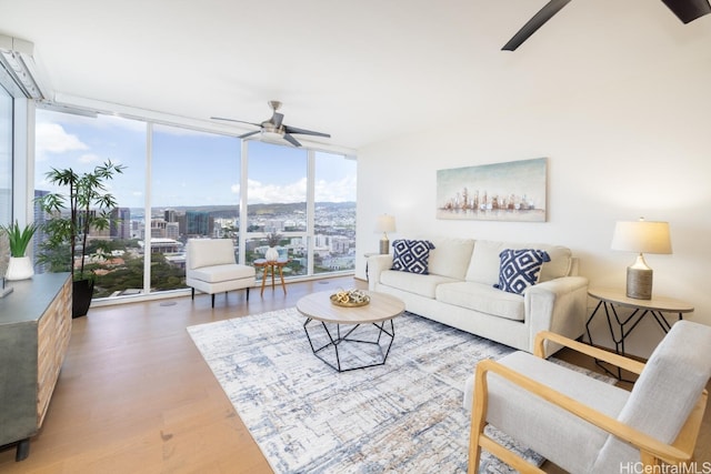 living room featuring ceiling fan, a healthy amount of sunlight, a wall of windows, and hardwood / wood-style floors