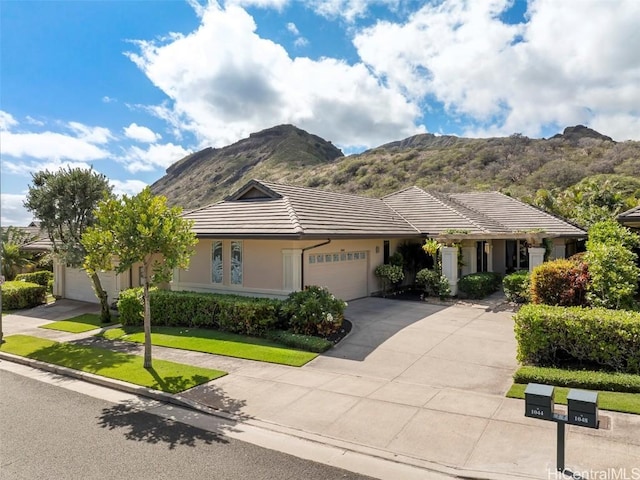 ranch-style home featuring a mountain view, a front lawn, and a garage