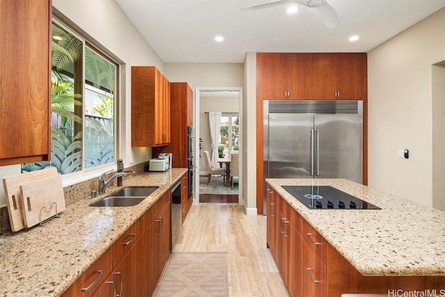 kitchen with appliances with stainless steel finishes, a center island, light hardwood / wood-style floors, and light stone counters