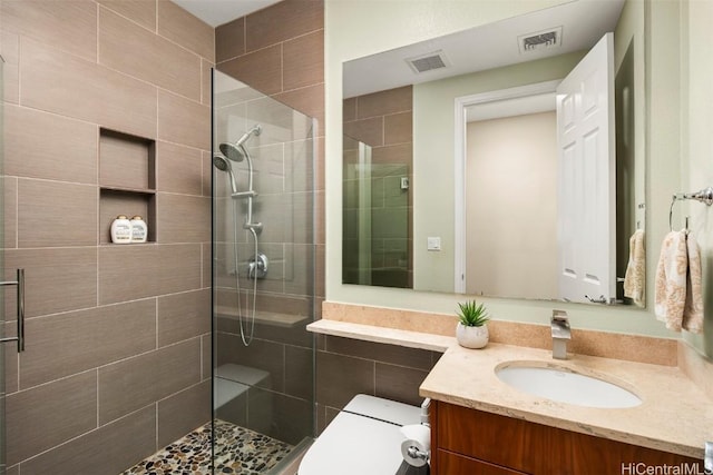 bathroom with vanity, a shower with shower door, and toilet