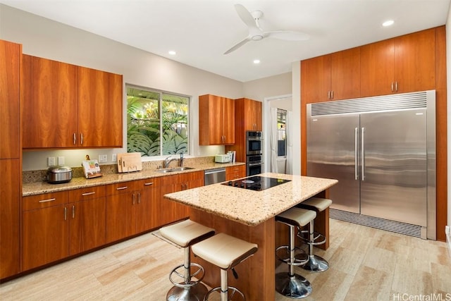 kitchen with a center island, sink, stainless steel appliances, a breakfast bar, and light wood-type flooring