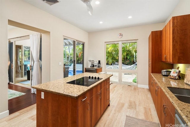 kitchen featuring light stone countertops, light hardwood / wood-style flooring, and a healthy amount of sunlight